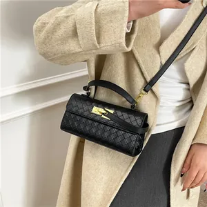 Classic black woven leather handbag with a gold twist lock on a beige coat model