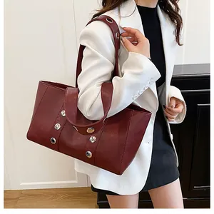 Macro detail of wine red tote bag with silver metal rivets and wide shoulder strap