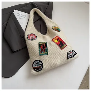 Detailed close-up of cream knit tote bag with vibrant mythical creature embroidery patches