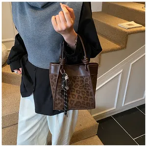 Détail du sac seau léopard avec poignée nouée et finitions en cuir synthétique marron chic