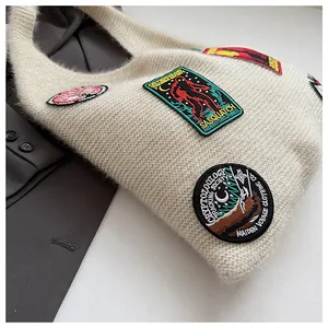 Macro shot of cream knit tote bag featuring vintage embroidery patches and soft texture