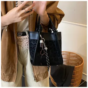 Détail du sac cabas léopard noir avec poignée nouée et breloques décoratives