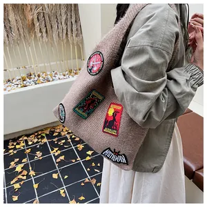 Detailed macro view of large knit tote bag featuring colorful mythical creature patches
