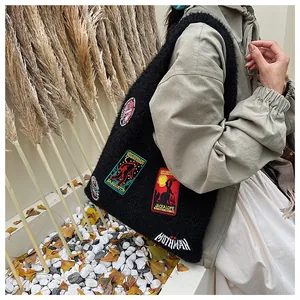 Detail of black fuzzy tote bag featuring colorful mythical creature embroidered patches