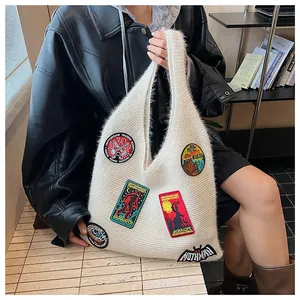Close-up of cream knit tote bag featuring colorful mythical creature embroidery patches
