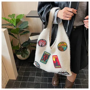 Detail of cream knit tote bag showing colorful embroidered mythical creature patches