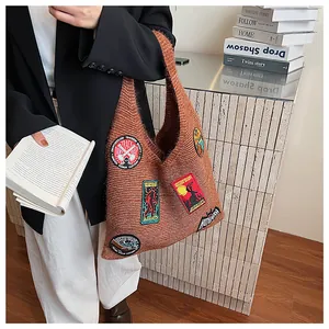 Detail of a brown knit tote bag with colorful mystery creature embroidered patches