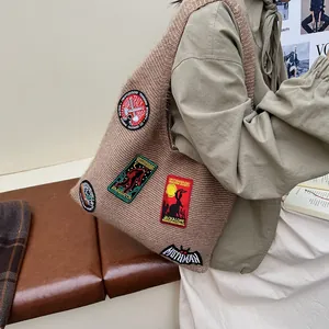 Brown knitted tote bag with mystical creature badges like Mothman and Sasquatch