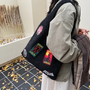 Black plush tote bag with embroidered mystery badges and large capacity for autumn