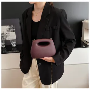Detalle del bolso de media luna burdeos en piel mate con cadena dorada y asa calada