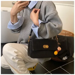 Detail der schwarzen Wildleder-Schultertasche mit Goldschließe und Blumenanhänger