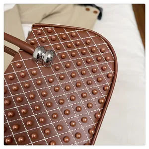 Primer plano de bolso acolchado marrón con cuentas decorativas y herrajes plateados
