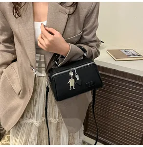 Dettaglio della borsa rettangolare in pelle PU nera con ciondoli robot in metallo