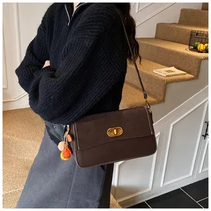 Detail der braunen Lederhandtasche mit Goldverschluss und buntem Perlen-Quastenanhänger
