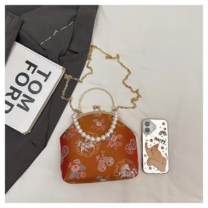 Detail of orange brocade shell bag with floral horse pattern and pearl top handle