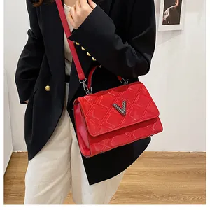 Gros plan du sac bandoulière en cuir matelassé rouge avec boucle en V argentée sur modèle