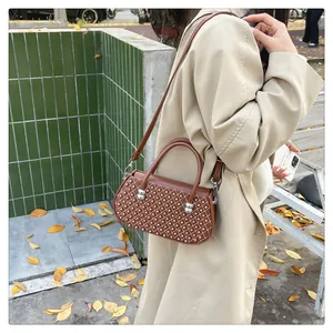 Detalle de bolso acolchado de cuero marrón con tachuelas plateadas y correa ajustable