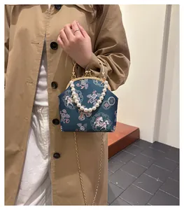 Detailed view of the beaded handle and embroidered floral satin shell bag with gold chain