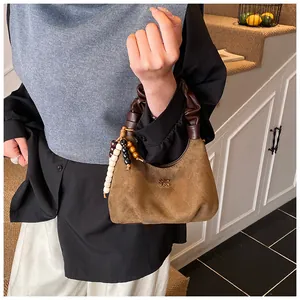Close-up of vintage suede handbag with pleated handle and colorful wooden bead detail