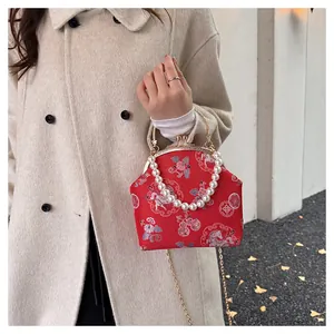 Detail of red New Chinese shell bag featuring traditional embroidery and pearl handle