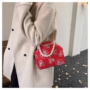 Detail view of red Chinese retro shell bag with pearl handle and floral embroidery