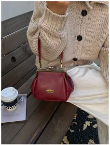 Gros plan d'un sac vintage bordeaux avec plaque en métal posé sur un banc en bois