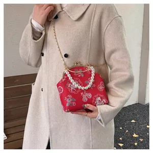 Detail of red brocade Chinese bag with pearl handle and traditional auspicious patterns