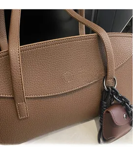 Detail of brown litchi grain leather tote bag with chain strap and small pouch charm