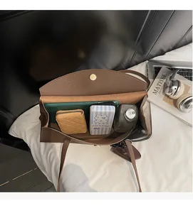 Spacious interior of dark brown litchi pattern leather bag holding a tablet and essentials
