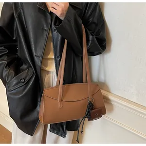 Chic brown leather shoulder bag with a mini charm pouch styled on a black leather jacket