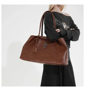 Detail of a brown retro tote bag featuring a metal cross pendant and textured faux leather