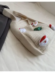 Close-up of knit texture on cream-colored Christmas shoulder bag with Santa patches
