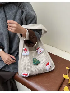 Close-up of knit handbag featuring plush Santa Claus dolls and a Merry Christmas tree