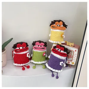 Detail of colorful knit bucket bags featuring funny cartoon faces and long hanging legs