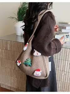 Detail of a brown knit tote bag featuring 3D Santa and Merry Christmas tree charms