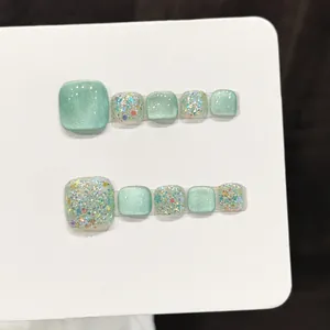 Mint green cat eye press-on toe nails with shimmering glitter and rhinestones