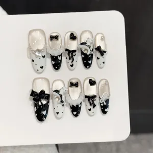 Long almond press-on nails featuring 3D cats, black bows, hearts, and polka dot designs