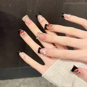 Handmade cherry press-on nails with black French tips and 3D rhinestones on pink base