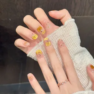 Short round press-on nails featuring hand-painted yellow apples and gold foil flakes
