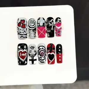 Unghie finte punk gotiche con croci 3D, rivetti e motivi a cuore scuri su carta bianca