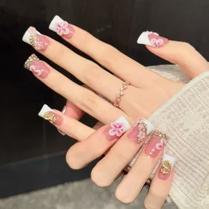 Pink press-on nails with 3D floral accents, dollar sign charms, and diamond details