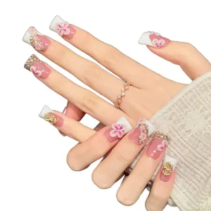 Luxurious pink and white French press-on nails with 3D floral petals and gold dollar charms