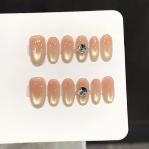 Cat eye press-on nails with peach gradient blush design and rhinestone accents