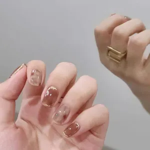 Detail of amber marble press-on nails with gold French tips and glossy finish