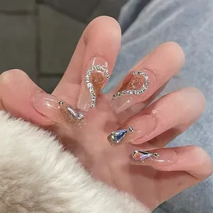 Detailed view of long ballerina press-on nails with pink base, glitter, and rhinestones