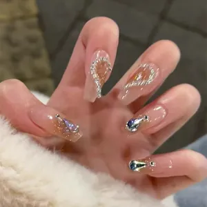 Detail of long ballerina press-on nails with nude pink gradient, rhinestones, and silver glitter