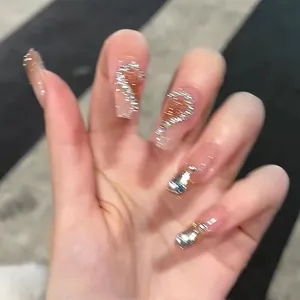 Detailed view of nude pink press-on nails with silver glitter curves and 3D rhinestones