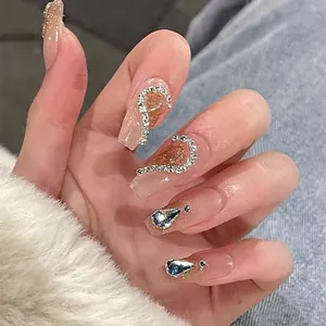 Detail of pink jelly press-on nails with champagne glitter and rhinestones on hands