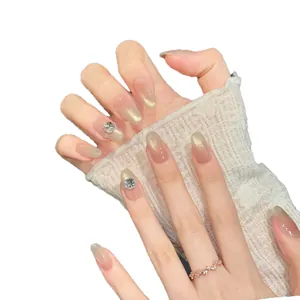 Almond-shaped press-on nails with peach blush cat eye gradient and rhinestone accents