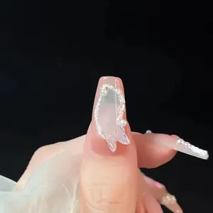 Gros plan d'ongles roses trapèze avec papillon 3D et perles décoratives élégantes